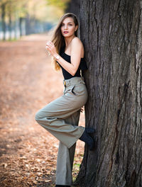 Portrait of woman standing by tree trunk