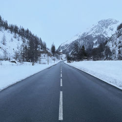 Road leading towards snowcapped mountain against sky