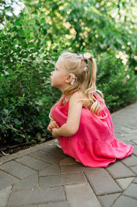 Portrait of young woman sitting on footpath