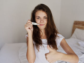 Portrait of beautiful young woman sitting on bed at home