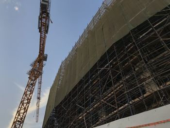 Low angle view of crane at construction site against sky