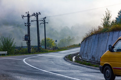 Car on road against sky during foggy weather