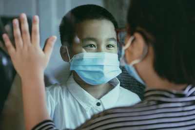 Cute boy wearing mask looking at sibling