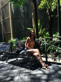 Young woman sitting on seat in yard