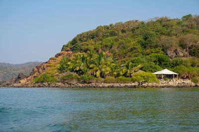 Scenic view of sea and trees against clear sky