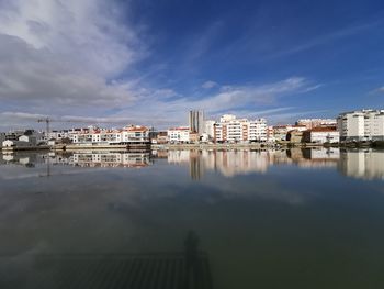 Reflection of buildings in sea against sky