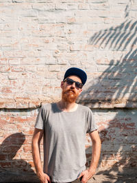 Young man wearing sunglasses standing against wall