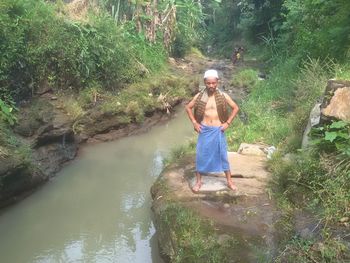 Full length of woman in stream amidst trees