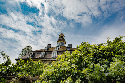 Low angle view of trees and building against sky