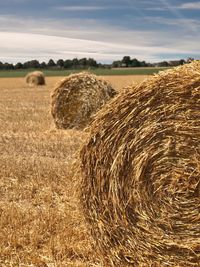 Hay bales on field against sky