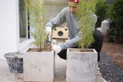 Man holding potted plant against trees