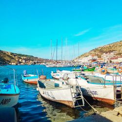 Boats moored at harbor against blue sky