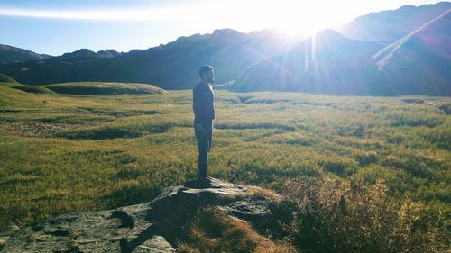 Man standing on grassy landscape against sky