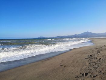 Scenic view of beach against clear blue sky