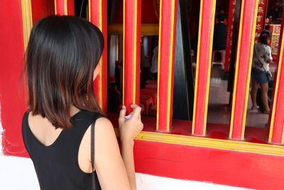 Rear view of woman looking through window