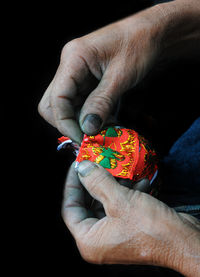 Cropped hands of man holding fabric over black background