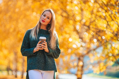 Young woman using smart phone during autumn