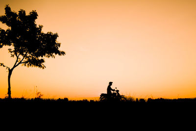 Silhouette man with arms raised against sky during sunset