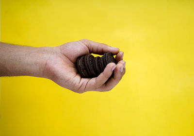 Close-up of hand holding food against yellow background