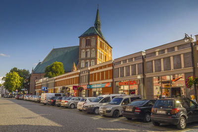 Cars on road by building against sky