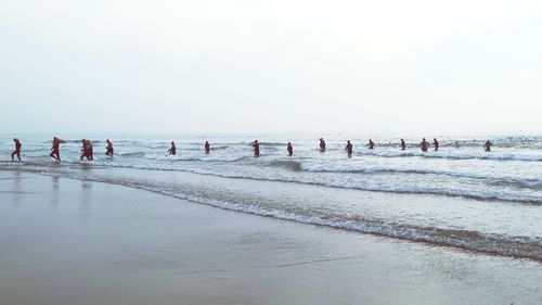 People on beach against clear sky