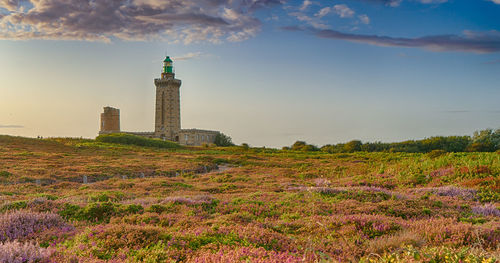 Lighthouse on field against sky