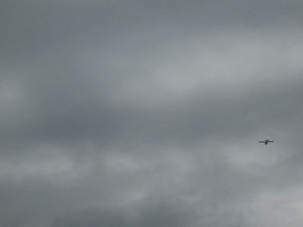 LOW ANGLE VIEW OF AIRPLANE FLYING OVER CLOUDS