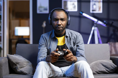 Portrait of young man using mobile phone while sitting on sofa at home