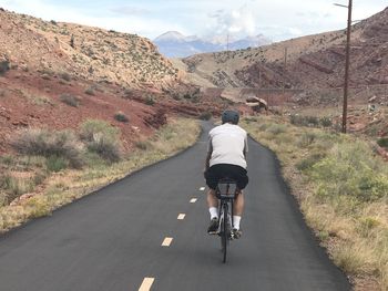 Rear view of man riding bicycle on road