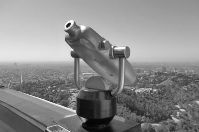 Close-up of coin-operated binoculars against cityscape