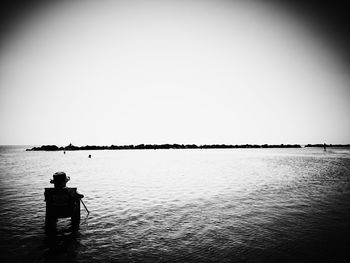 Rear view of man standing in sea against clear sky