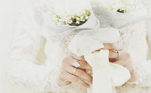 Midsection of bride holding bouquet