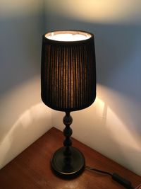 Close-up of lamp on table against wall at home