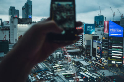 Close-up of hand photographing cityscape