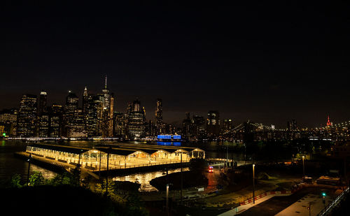 Illuminated bridge and buildings against sky at night