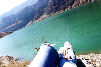 Low section of person on sea by mountain