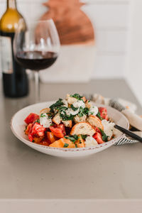 Italian pancanella salad in deep plate. fresh heirloom tomatoes. red wine in glass.