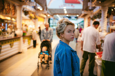 Portrait of young woman standing in illuminated market
