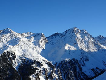 Scenic view of snowcapped mountains against clear blue sky