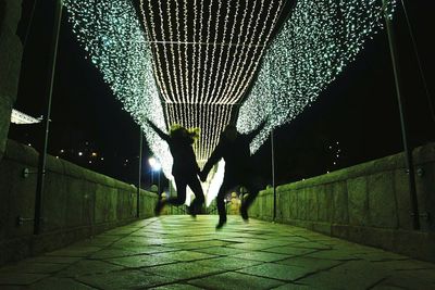 Man walking on sidewalk against sky at night