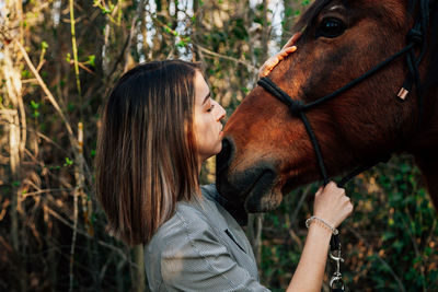Close-up of young woman standing with horse outdoors