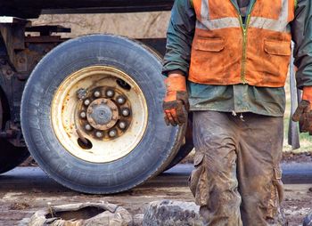 Midsection of construction worker walking against truck