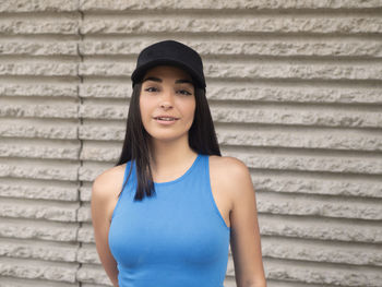 Portrait of young woman standing against wall