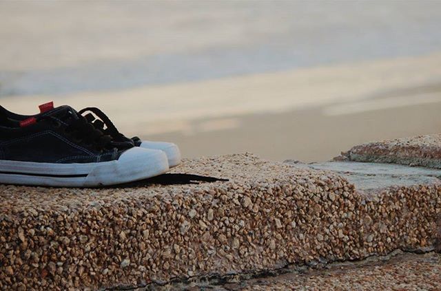 beach, sand, shore, sea, focus on foreground, sky, day, water, shoe, outdoors, rock - object, lifestyles, nature, stone - object, close-up, pebble, leisure activity, transportation