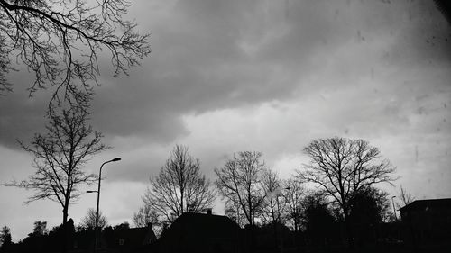 Low angle view of bare tree against cloudy sky