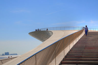 Rear view of man on staircase against blue sky