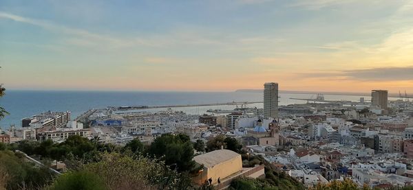 High angle view of buildings and sea against sky at sunset