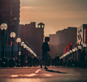 Man walking on street against sky during sunset