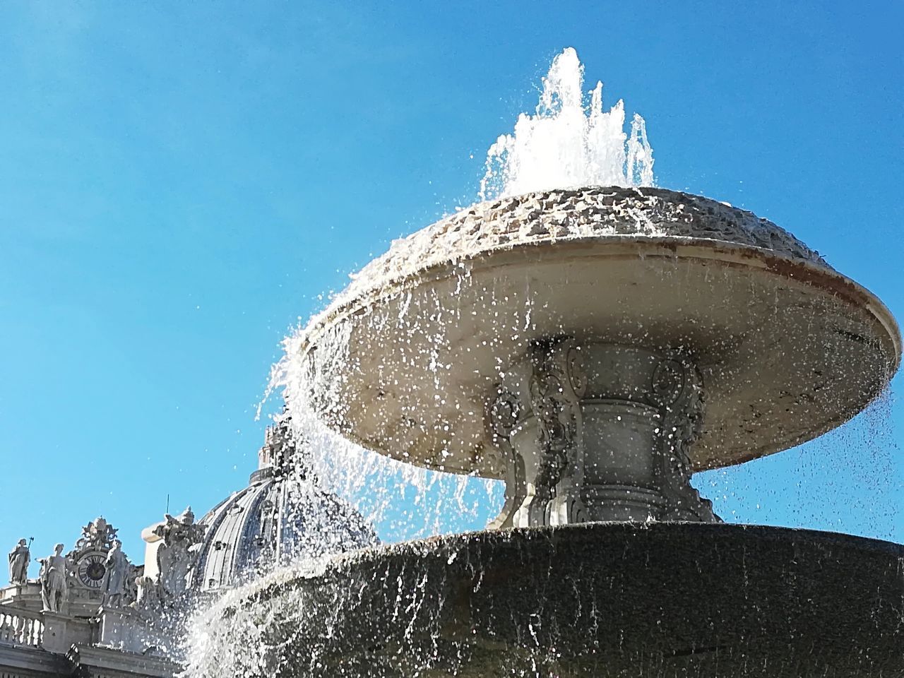 LOW ANGLE VIEW OF FOUNTAIN IN CITY AGAINST BLUE SKY