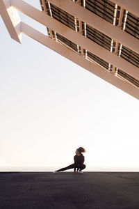 African american female athlete performing side squat during training under modern house while looking away in city